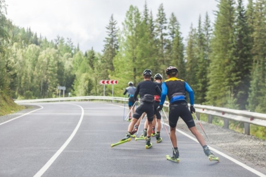 Träningsgrupp åker rullskidor på höger sida av vägen, skate